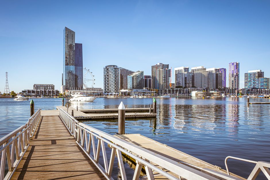 A modern commercial building in South Quay Docklands featuring a combination of materials including glass, concrete, and metal. The structure includes large glazed windows that reflect the surrounding